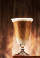 Cappuccino coffee in a glass goblet on the table