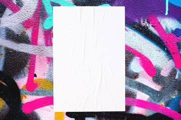 Closeup of colorful messy painted urban wall texture with wrinkled glued poster template . Modern mockup for design presentation. Creative urban city background. 