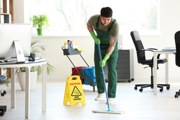 Male janitor mopping floor in office