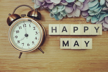 Happy May alphabet letters with alarm clock on wooden background