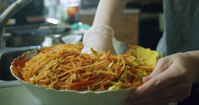 Mixing in Korean chili paste (gochu jang) in with jjolmyeon noodles to create Korean Spicy Chewy Noodles in a large bowl.