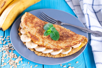 Breakfast oatmeal pancakes with banana and mint on a blue wooden background. Easy and quick breakfast. Healthy breakfast concept