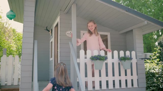 Cute little sisters watering flowers in their playhouse.