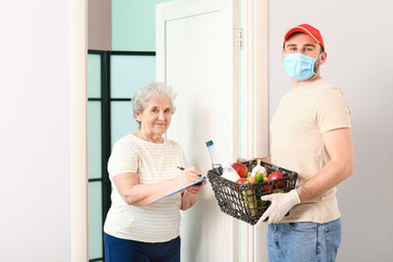 Senior woman receiving food from courier at home. Concept of epidemic