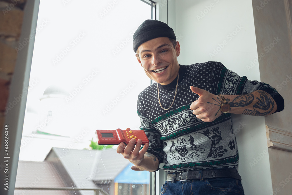 Wall mural Portrait of millenial boy using retro toys, meeting things from the past and having fun. Generation of digital devices explores past entertainment. The memories of early childhood, again in trend.