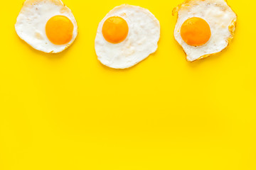 Fried eggs pattern on yellow background top view copy space