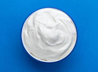 Bowl of sour cream on blue background