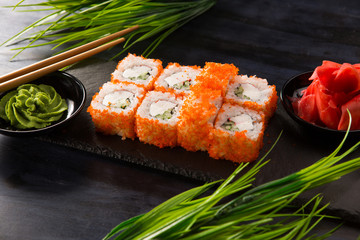 Set of sushi rolls with wasabi and ginger on a black background. Japanese oriental cuisine