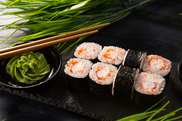 Set of sushi rolls with wasabi and ginger on a black background. Japanese oriental cuisine