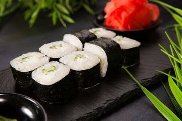 Set of sushi rolls with wasabi and ginger on a black background. Japanese oriental cuisine