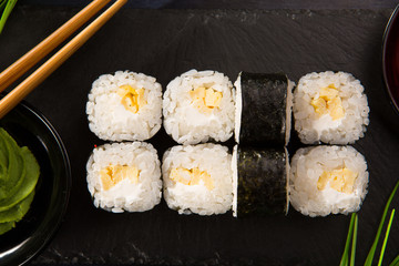 Set of sushi rolls with wasabi and ginger on a black background. Japanese oriental cuisine