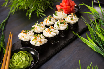 Set of sushi rolls with wasabi and ginger on a black background. Japanese oriental cuisine