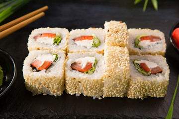Set of sushi rolls with wasabi and ginger on a black background. Japanese oriental cuisine