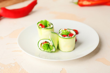 Plate with tasty cucumber rolls on white background