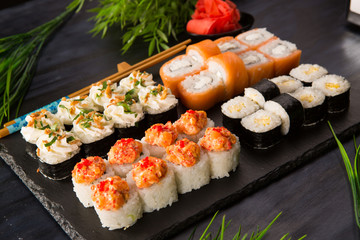 Set of sushi rolls with wasabi and ginger on a black background. Japanese oriental cuisine