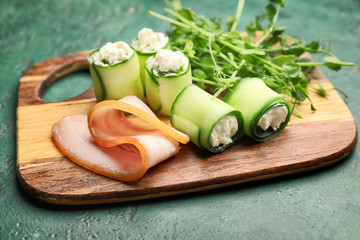 Board with tasty cucumber rolls on table
