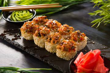 Set of baked sushi rolls with wasabi and ginger on a black background. Japanese oriental cuisine © Alik Mulikov