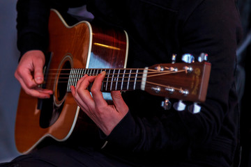 Hands holding a guitar. Make hands while playing guitar in recording Studio. Concept of learning to play the guitar