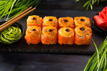 Set of baked sushi rolls with wasabi and ginger on a black background. Japanese oriental cuisine