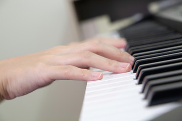 Fototapeta na wymiar Closeup of hands playing piano lateral view. Selective focus. Hobby during staying at home. 