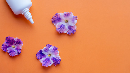White spray can with violet flowers on orange background. Creative flat lay, copy space. Flower allergy concept