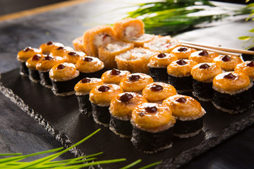Set of baked sushi rolls with wasabi and ginger on a black background. Japanese oriental cuisine