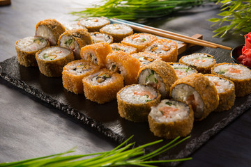 Set of fried sushi rolls with wasabi and ginger on a black background. Japanese oriental cuisine