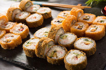 Set of fried sushi rolls with wasabi and ginger on a black background. Japanese oriental cuisine