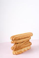 Vertical image.Stack of shortcrust cookies on the pink surface against white background
