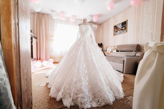 A white wedding dress is worn on a mannequin in the middle of the room
