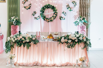 Decoration of a wedding table of greenery, flowers and roses, candles. LED hearts backlight