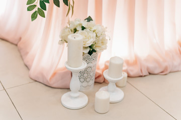 White candles on a stand on the floor near the table and a pink tablecloth