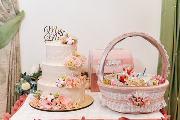 Three-tier wedding cake nested with flowers and roses
