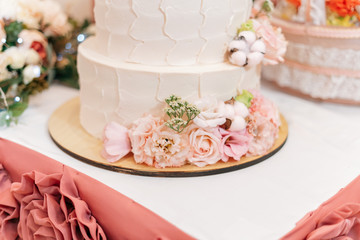 Three-tier wedding cake nested with flowers and roses
