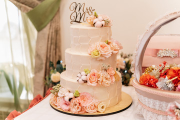 Three-tier wedding cake nested with flowers and roses