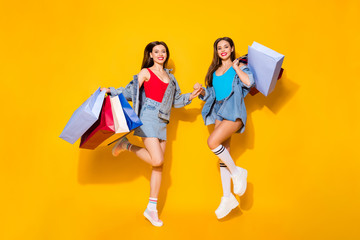 Full length body size view of nice attractive pretty glamorous slender cheerful girls carrying buyings jumping shadow friends friendship isolated on bright vivid shine vibrant yellow color background