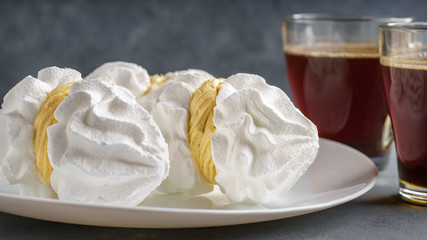 Bizete cakes on a plate next to cups of coffee