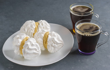 Bizete cakes on a plate next to cups of coffee