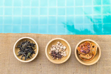 Variety of spice and herbs in wooden bowl with space on blue water background, tea and spice with dry fruit, healthy food