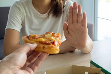 The woman takes care health and weight refuse a piece of pizza that her friend sent. Good health...