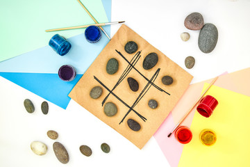 top view of tic tac toe game with stones marked with naughts and crosses. Children's art project, a...