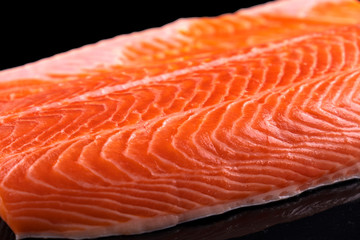 Uncooked fish fillet isolated on black. Raw salmon fillet. Closeup, macro view