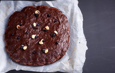 square whole baked brownie chocolate cake with nuts on white parchment paper