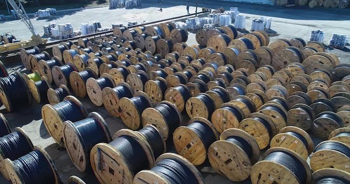 Span over baboons with cable, large coils with wire under the open sky. Warehouse near the cable factory