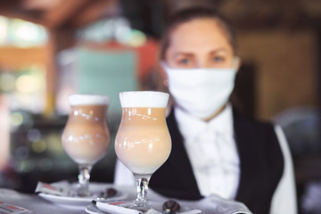 bartender in medical mask and gloves makes latte coffee.