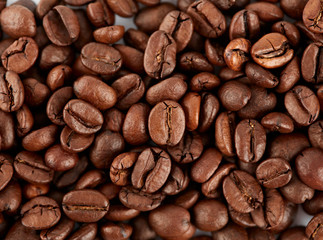 Roasted coffee beans on a white background. The texture of the coffee. An invigorating drink.