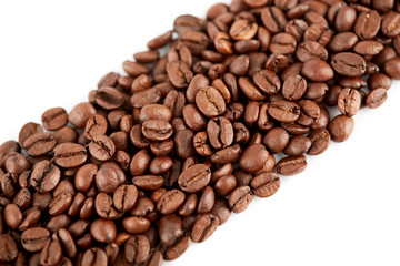 Roasted coffee beans on a white background. The texture of the coffee. An invigorating drink.