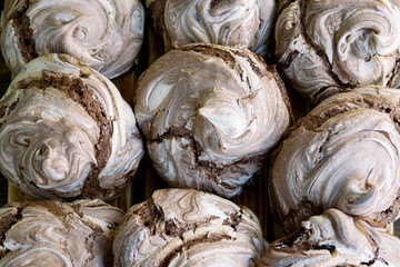 Fototapeta na wymiar Homemade chocolate meringue cookies - wallpaper, bakery background with top close up view. Italian or French crunchy dessert made of eggs and sugar. Natural light.