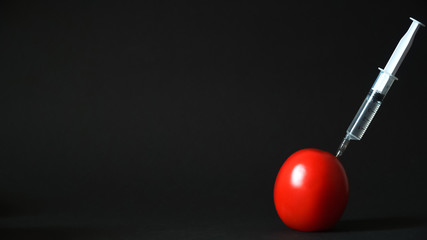 Syringe in a tomato on a black background