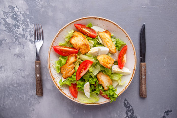 Chicken and vegetables salad served with fork and knife. Top view